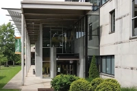 The entrance to the Insalaco Studio Arts Center with white pillars supporting the front, large windows, and a glass door as the entrance